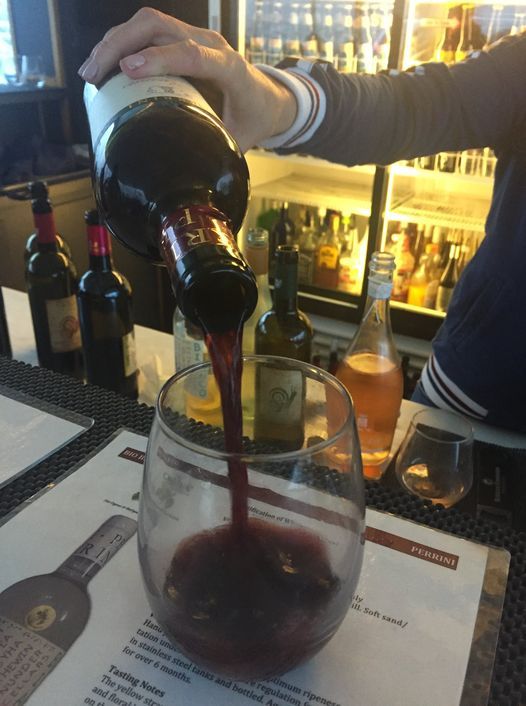 Red wine being poured into a glass on a Dana Wharf wine cruise