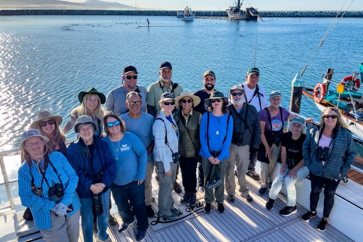 a group of people posing in front of a body of water