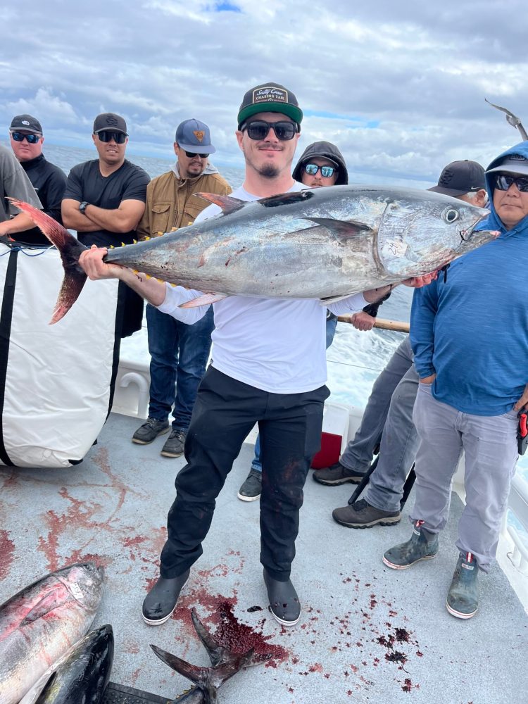 a group of people standing next to a person holding a fish