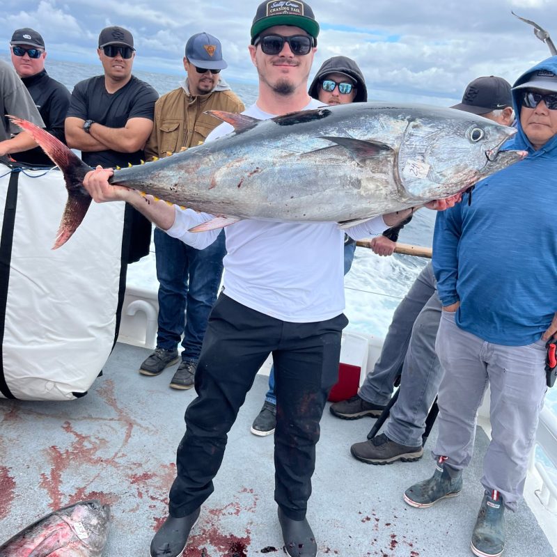 a group of people standing next to a person holding a fish