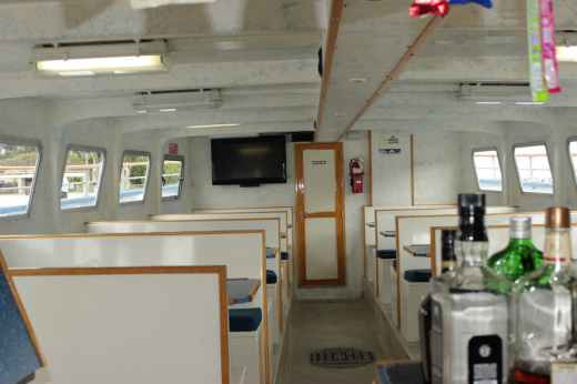 The Dana Pride's main salon with table seating, a flat-screen TV and the bar