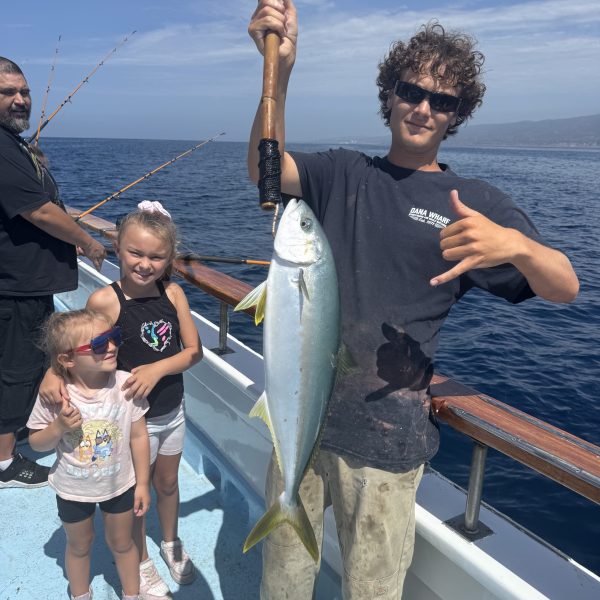 Person holding a large fish on a boat with children nearby.