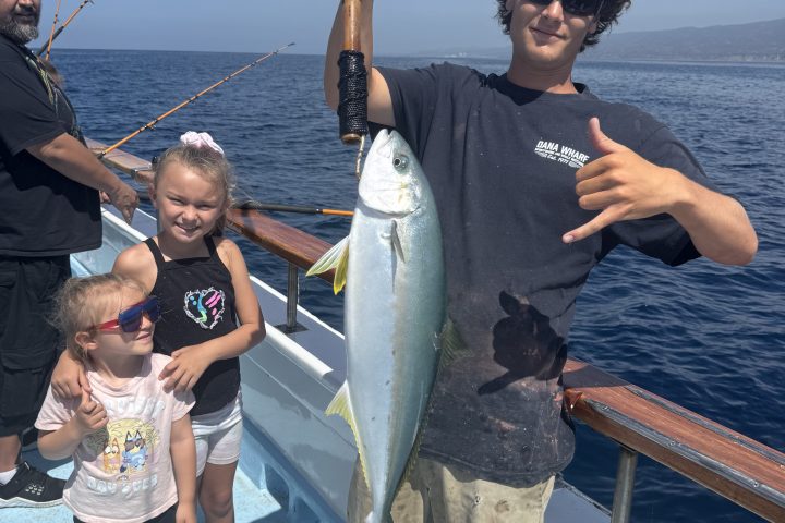 Person holding a large fish on a boat with children nearby.