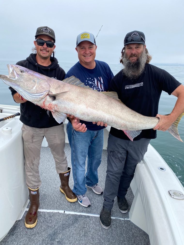 Three anglers holding a large fish aboard the Current
