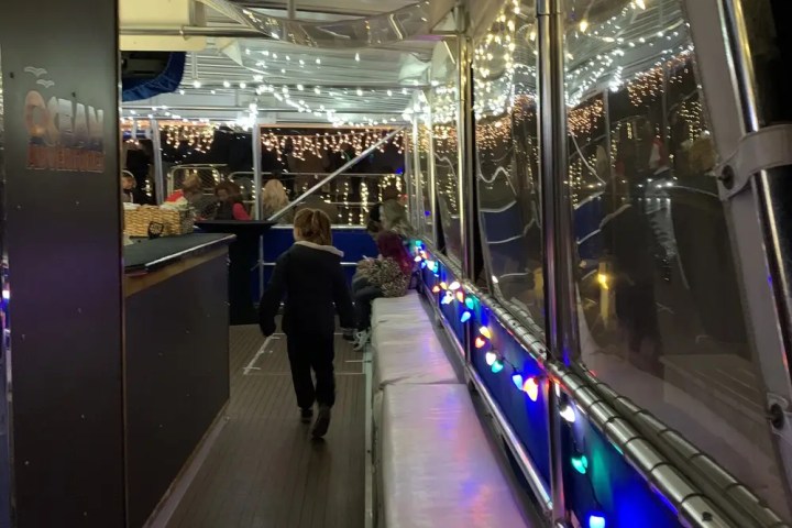 Child walking on a boat deck adorned with festive string lights.