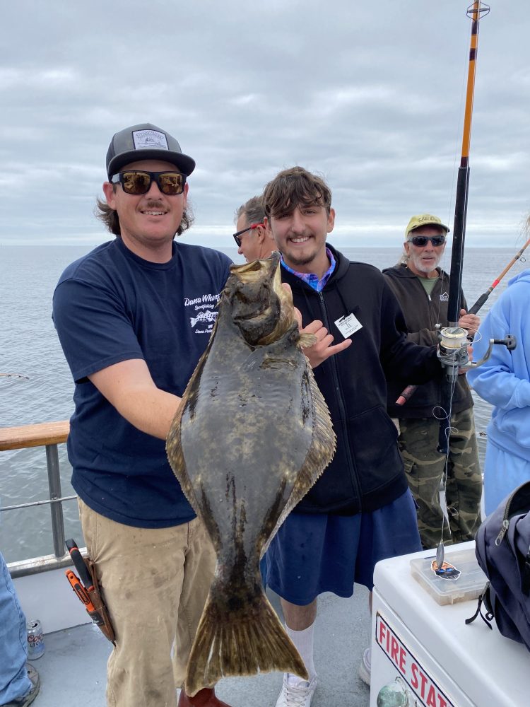 a group of people standing next to a person holding a fish