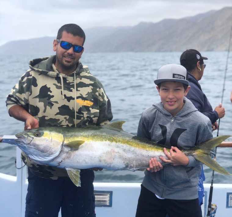 Two anglers holding a large catch aboard the Fury