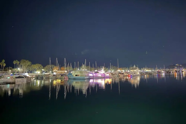 Marina at night with boats and lights reflecting on water.