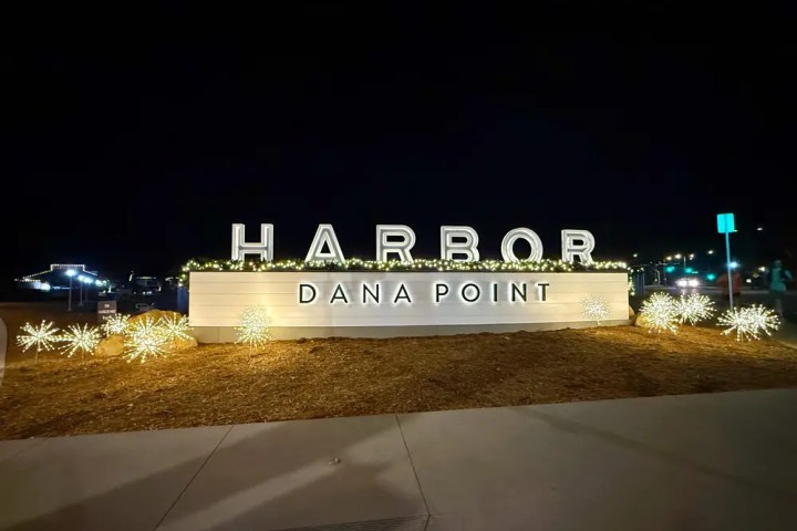 Illuminated 'Harbor Dana Point' sign at night with decorative lights.
