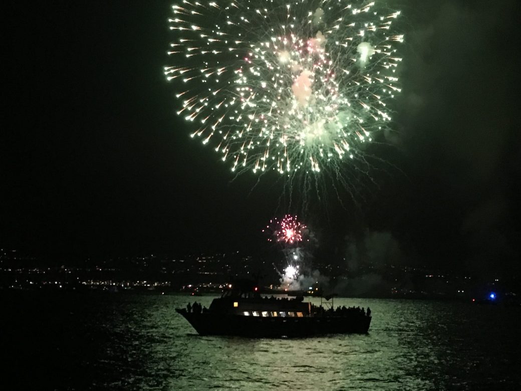 Fourth of July fireworks over the water seen from a Dana Wharf boat