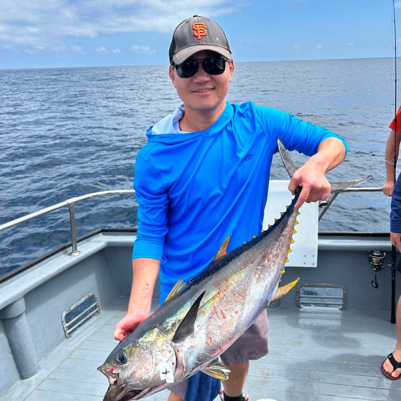 a man holding a fish on a boat in a body of water