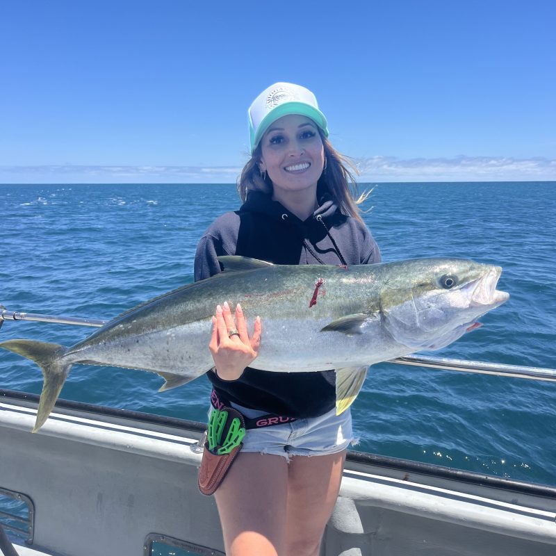Person holding a large fish on a boat in sunny weather
