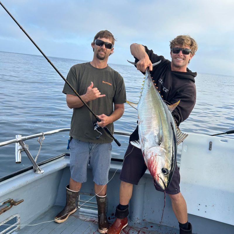 a man holding a fish on a boat in the water