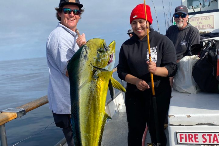 a group of people standing next to a person holding a fish