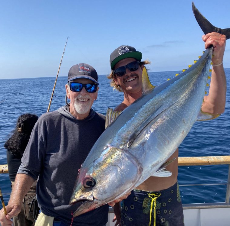 Two anglers holding a tuna aboard the Clemente