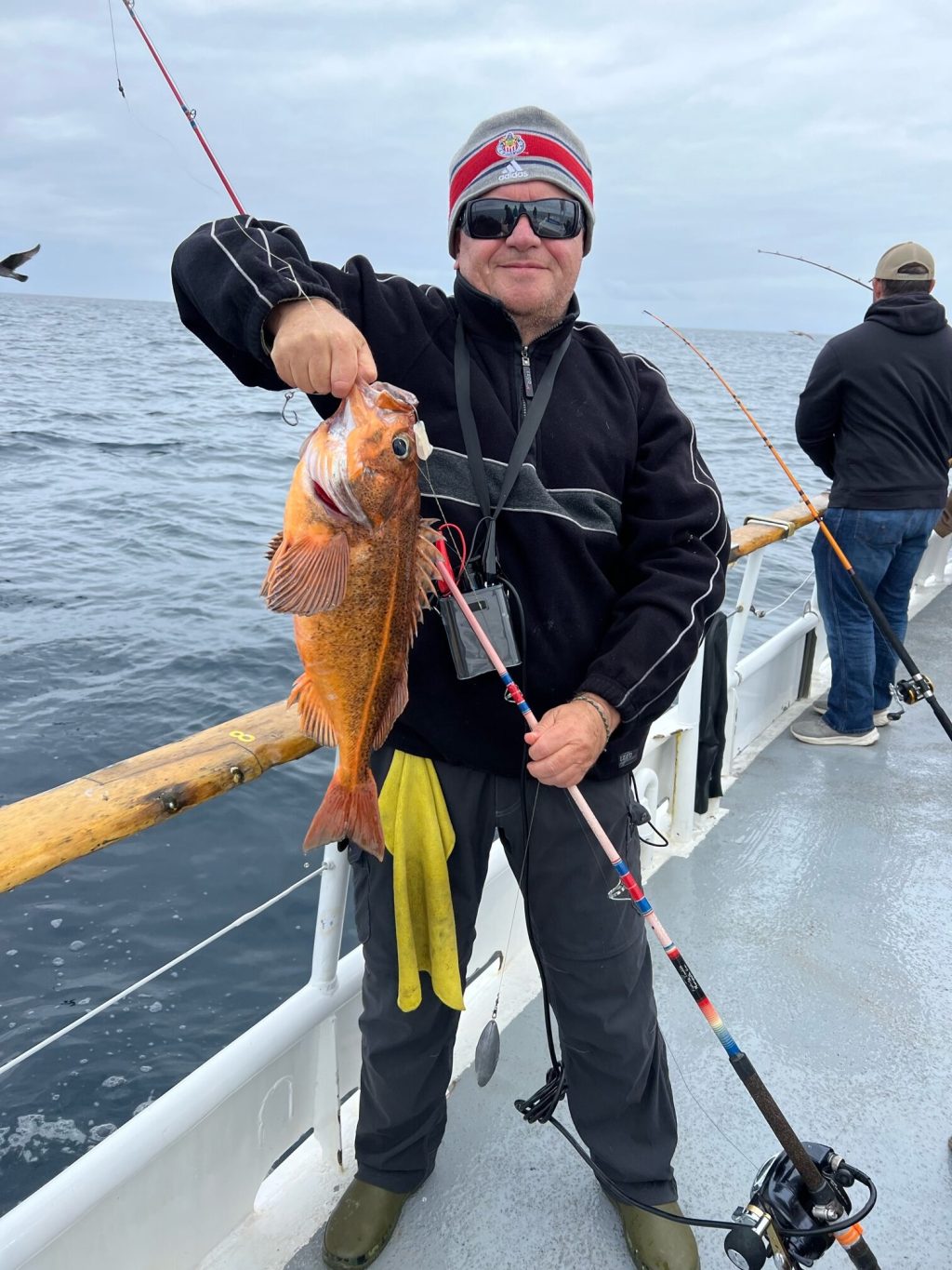 a man holding a hot dog on a boat in the water