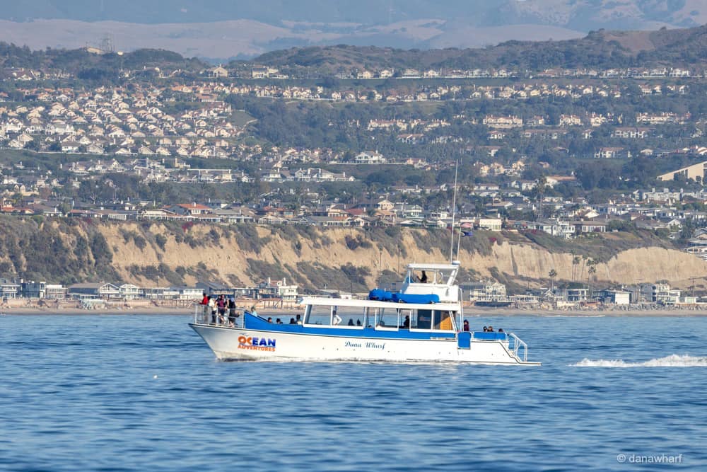 a large boat in a body of water with a mountain in the background
