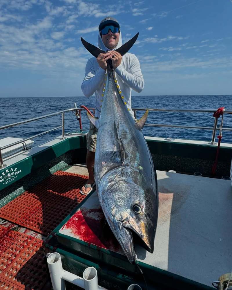 a man holding a fish on a boat in a body of water