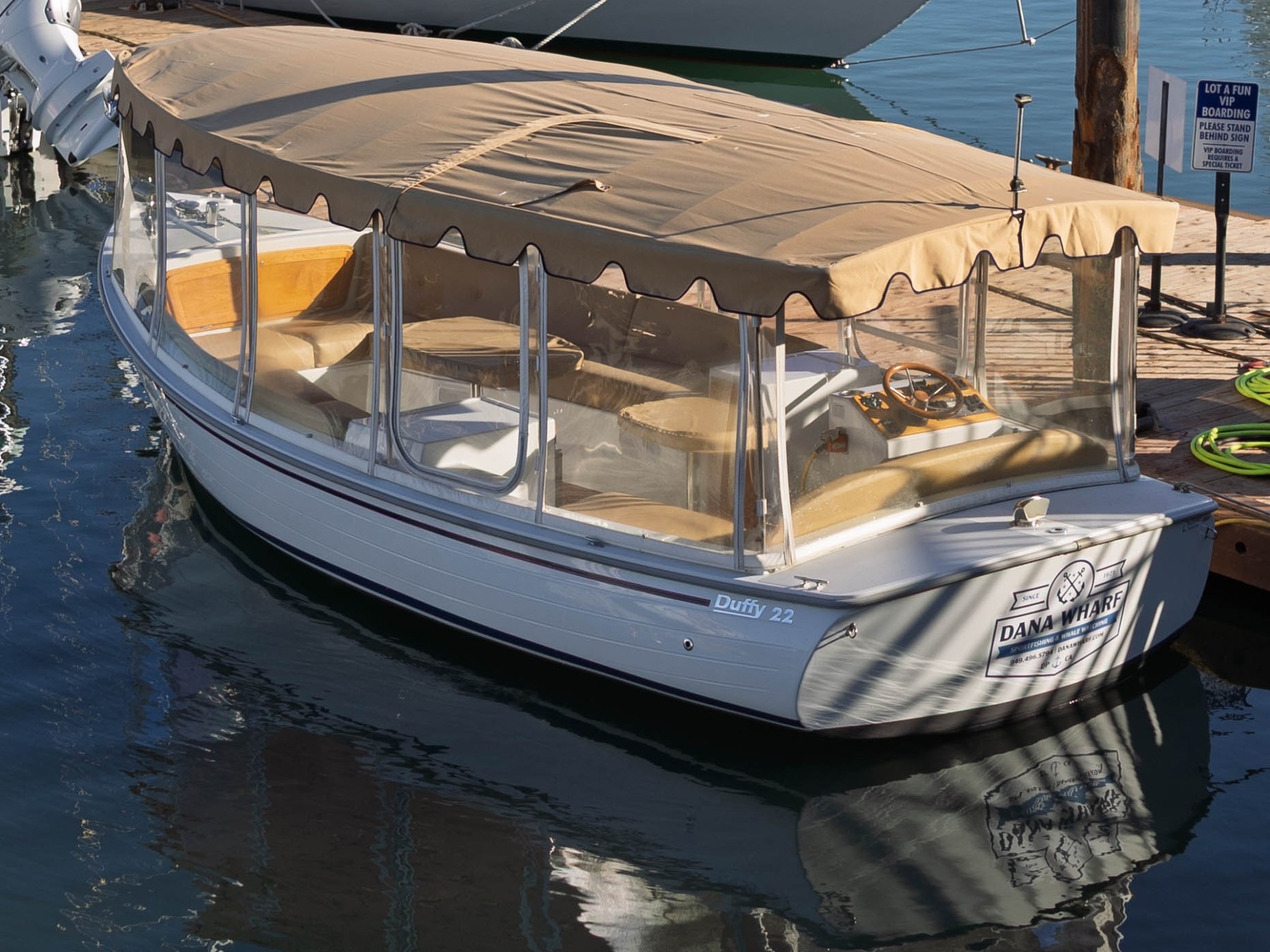 Small covered boat docked with reflections on the water.