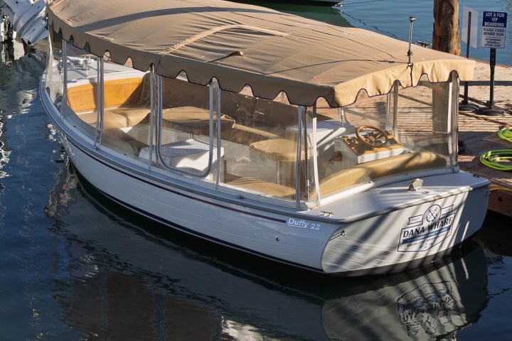 Small covered boat docked with reflections on the water.