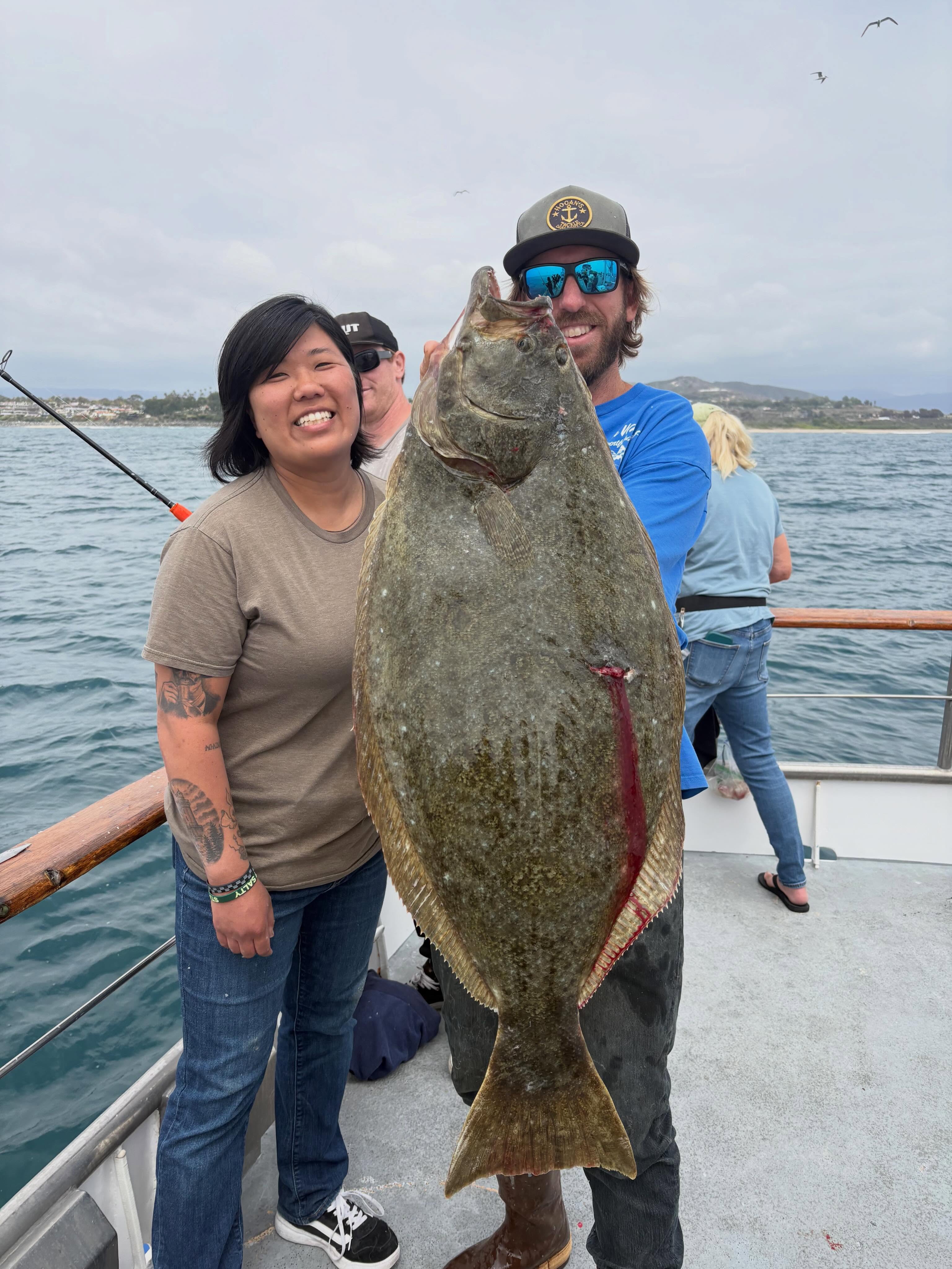 Anglers hold up a halibut caught aboard the Clemente on a half-day deep sea fishing trip out of Dana Point