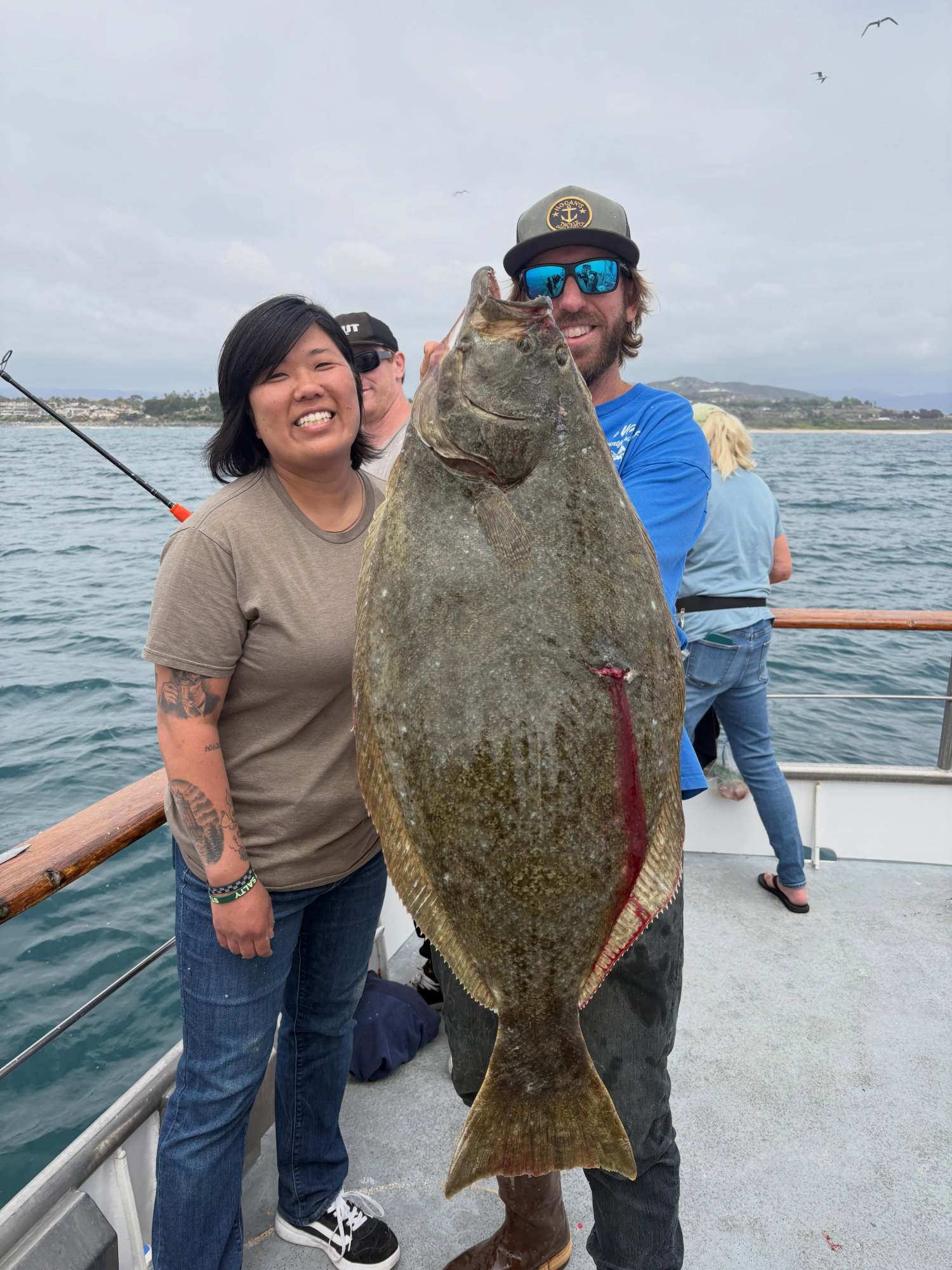 Anglers hold up a halibut caught aboard the Clemente on a half-day deep sea fishing trip out of Dana Point