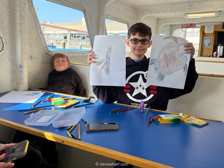 Kids showing off whale drawings from the Wyland art lesson aboard a Dana Wharf whale watching boat in Dana Point in February