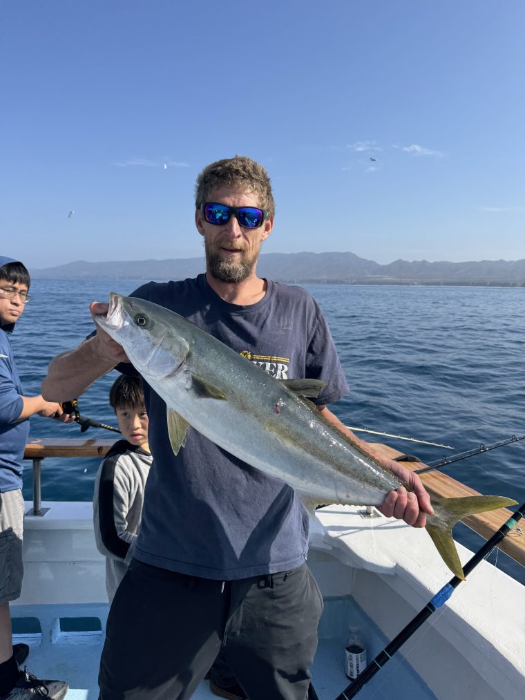 Angler holding a yellowtail aboard the Helena