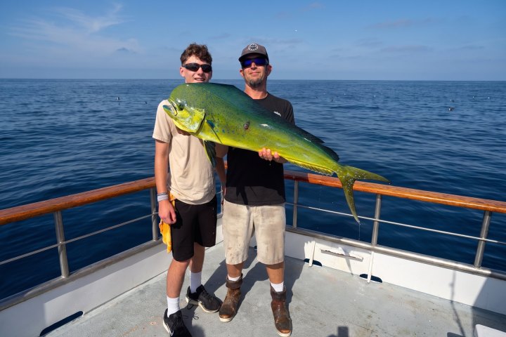 Two anglers holding a dorado on a Dana Wharf 10-hour offshore fishing trip