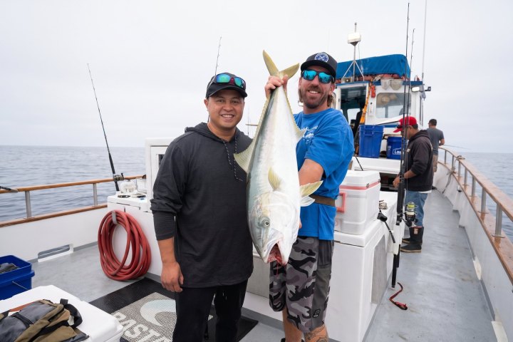 Two anglers holding a yellowtail on a Dana Wharf fishing trip