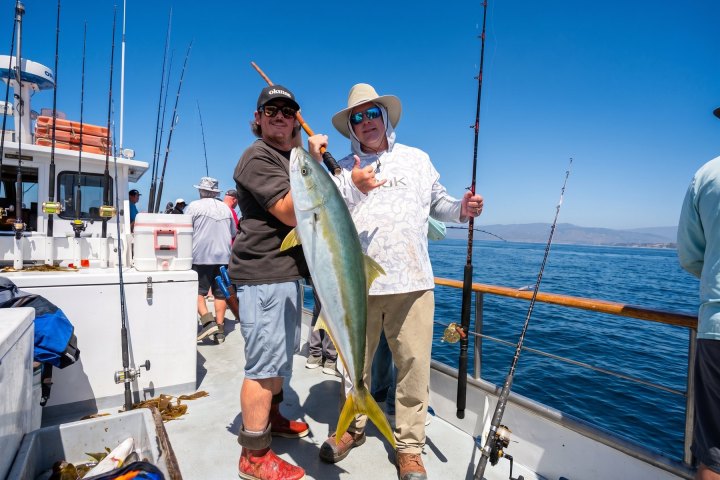 Two anglers holding a yellowtail on a Dana Wharf fishing trip