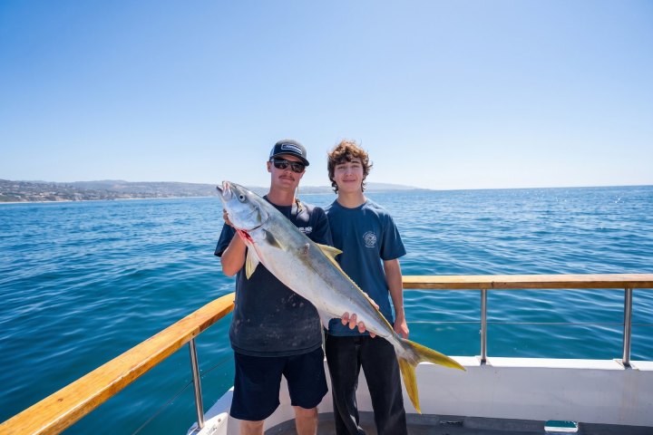 Two anglers holding a yellowtail on a Dana Wharf 3/4-day fishing trip
